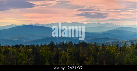 Wide angle panorama autumn forest,misty hills mountain tops in pink dawn. Stock Photo
