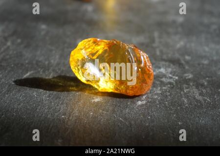 Piece of amber on gray slate background, lit by the sun Stock Photo