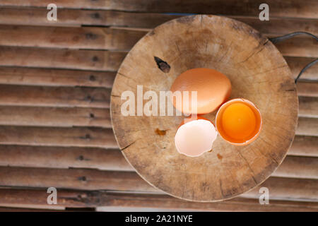 Brown eggs on a wooden chopping board There is a yolk in the egg shell. The brown egg has a drop of water because it is removing from the refrigerator Stock Photo