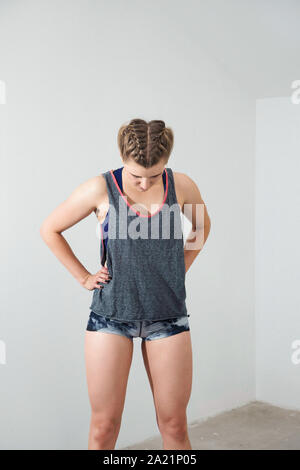 Young blonde woman in boxer braids resting after workout, wearing comfortable sporty outfit. Stock Photo