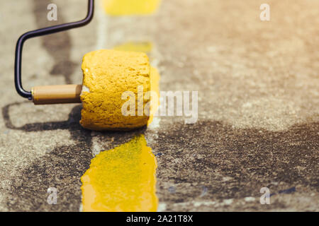 Male students use small paint rollers to paint yellow lines on the cement floor for Sepak Takraw training. Stock Photo