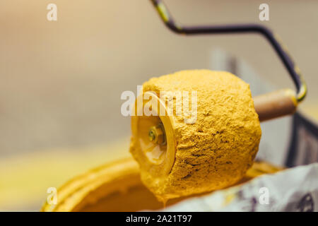 Male students use small paint rollers to paint yellow lines on the cement floor for Sepak Takraw training. Stock Photo