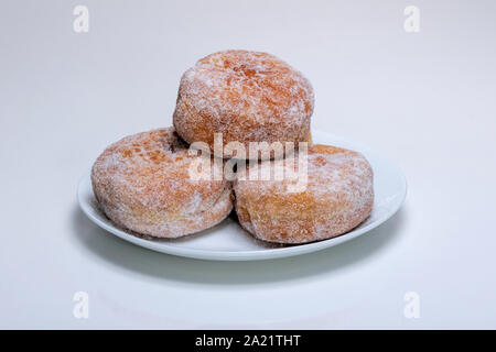 a stack of sugared jam jelly doughnuts on a white plate with a white background. Stock Photo