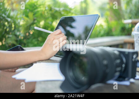 Photographer sitting and editing photos using a tablet. Portable size, smart features In a coffee shop or café Stock Photo