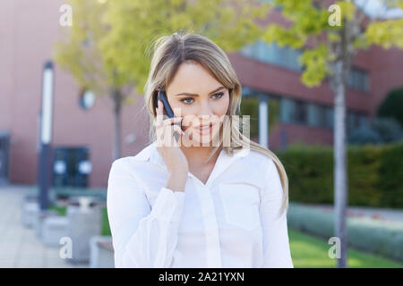 Serious blonde manager woman portrait calling in park Stock Photo