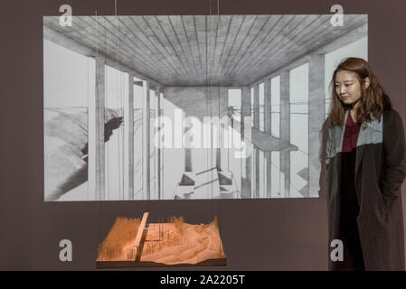 London, UK.  30 September 2019. A staff member poses next to 'Bird's Monastery after collapsion', 2019, and a video 'Bird's Monastery', 2017, both by Seung H-Sang. Preview of 'Negotiating Borders', an exhibition organised by the Real DMZ Project exploring the history and future of the DMZ (Demilitarised Zone), the four kilometre wide invisible military borderline at which North and South Korea face each other.  Works by seven Korean artists is on display at the Korean Cultural Centre UK, 1 October to 23 November 2019.  Credit: Stephen Chung / Alamy Live News Stock Photo