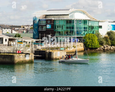 Sailing vessel Jamala exits Sutton Harbour towards Plymouth Sound.  Plymouth Marine Laboratory in the background Stock Photo