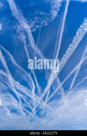 Multiple contrails (or chemtrails) from aircraft high in blue sky over central France. Stock Photo