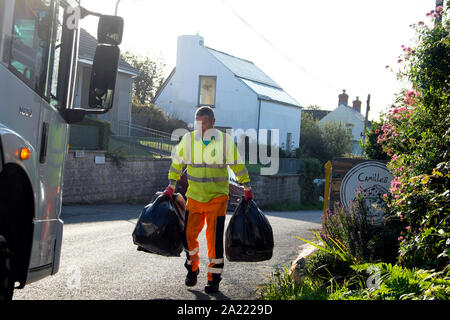 Council worker with black plastic bags and lorry collecting household rubbish in the village of Marloes Pembrokeshire in West Wales UK  KATHY DEWITT Stock Photo