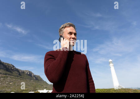 Man standing near lighthouse using smartphone Stock Photo