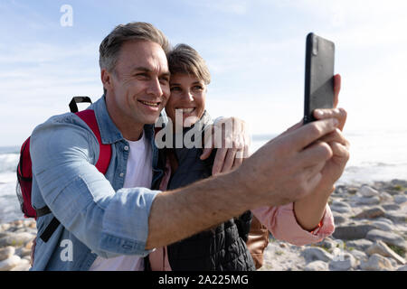 Couple using smartphone by the sea Stock Photo