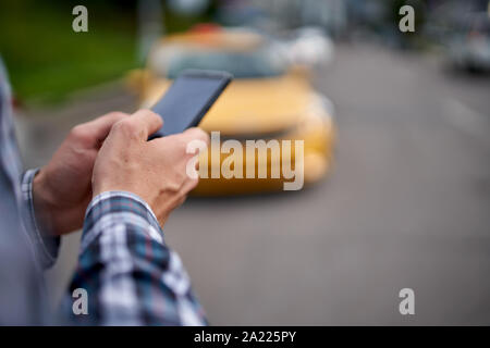 Photo of mans hands with phone in his hands on blurry background taxi summer day Stock Photo