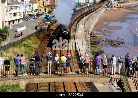 People on a footbridge watching the Royal Duchy rail-tour passing through Dawlish, hauled by LMS Pacific No 6233 'Duchess of Sutherland'. 15.09.2019. Stock Photo