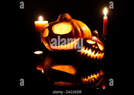 Image of halloween pumpkins with burning mouths, candles on empty black background in studio Stock Photo