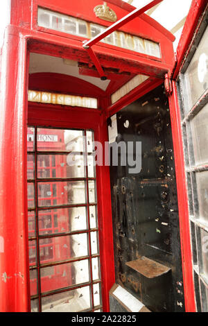 Traditional red British telephone box with the telephone removed.