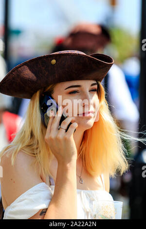 Pirate Day, Hastings. Beautiful Caucasian young woman with nose ring and long dyed blonde hair, holding mobile cellphone to ear while looking ahead. Stock Photo