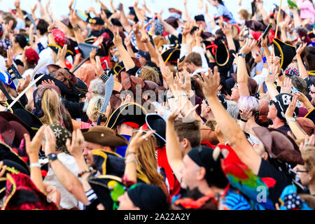 Pirate Day in Hastings, UK. Mass of people dressed as pirates crowded into waving while on the beach for the world record attempt. Stock Photo