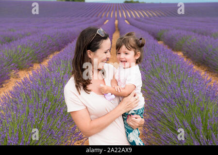 Happy mother and daughter walking among lavender fields in the summer Stock Photo