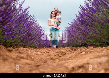 Happy family walking among lavender fields in the summer Stock Photo