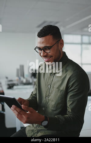 Handsome young african american businessman sitting in office smiling while using a smartphone Stock Photo