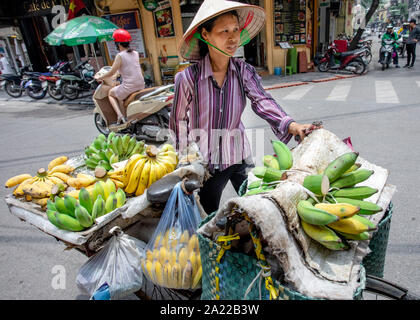 Traditional street fruit seller on bicycle at Hanoi, Vietnam. Woman selling bananas at street of Vietnam. Stock Photo