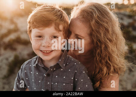Front view of mother hugging redheaded kindergarten age son at sunset Stock Photo