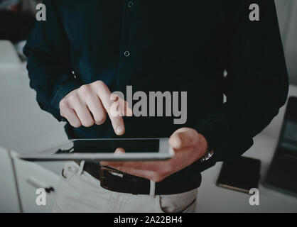 Mid section of a well dressed businessman touching his digital tablet screen with finger Stock Photo