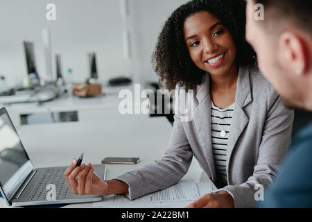 Motivated positive female leader talking with male coworker explaining project and plans at workplace Stock Photo