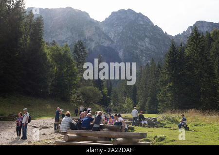 Polish hikers rest on seats and benches on the footpath leading towards the climb up to Sarnia Skala, a mountain in the Tatra National Park, on 16th September 2019, near Koscielisko, Zakopane, Malopolska, Poland. Stock Photo