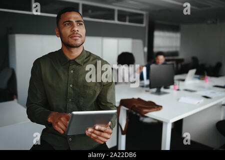 Thoughtful young businessman thinking on productive strategy using digital touch pad device in modern office Stock Photo