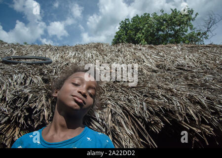 Afro-Brazilian girl from a quilombo leaning on a straw roof outdoors Stock Photo