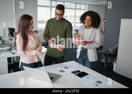Multiethnic coworkers team working new startup project at modern office analyzing business documents, using digital tablet and mobile phone Stock Photo