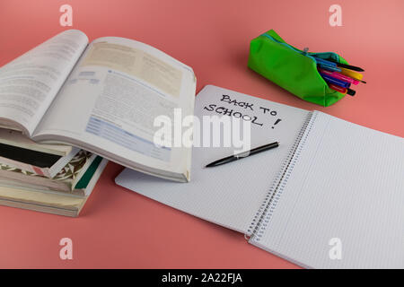 Back to school concept, books and open notebook with the words back to school written on it, on a pink background Stock Photo