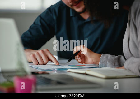 Close-up of businessman and businesswoman working together with statistics on office desk Stock Photo