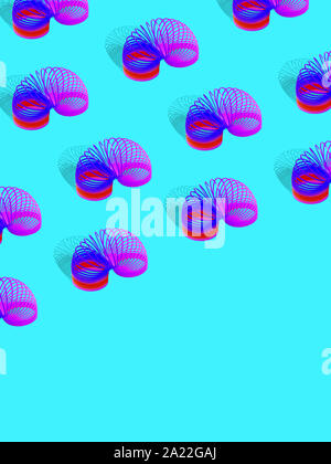 Slinky toy pattern Minimal style Many spring toys are standing in rows on a blue background Design template with empty space Stock Photo