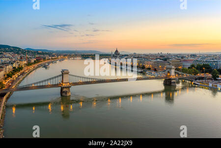 Chain bridge in Budapest, Hungary. Danube river with boats. Evening traffic with light trails.