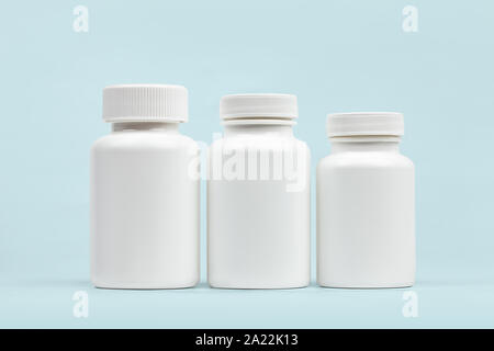 Blank medical plastic vitamin bottles set on light blue background Stock Photo