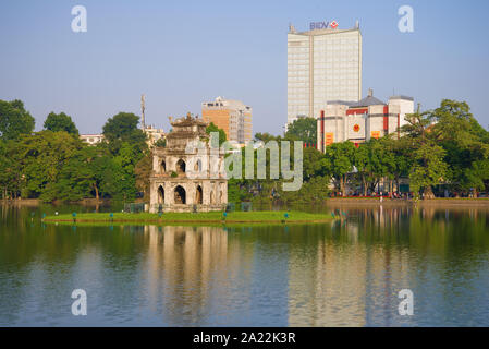 HANOI, VIETNAM - DECEMBER 13, 2015: Turtle tower on the background of modern buildings on the embankment of Hoan Kiem lake on a sunny morning