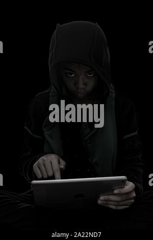 Hacker boy are hacking through the tablet on a black background. Stock Photo
