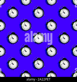 Many black classic style alarm clock with hard shadow isolated on blue background. Smile time concept. Seamless pattern Stock Photo