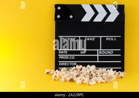 Popcorn and clapperboard on colorful background. Stock Photo