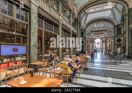 People sitting at tables eating food in the indoor ,art deco,glass ceilinged  arcade ,Galleria San Federico in Turin ,Italy