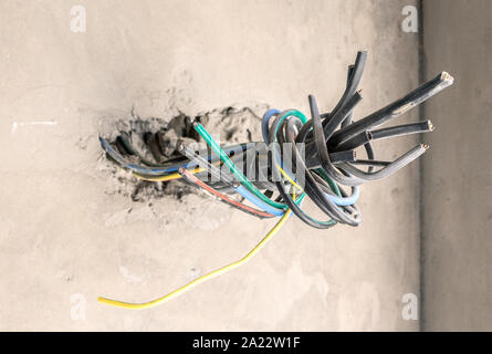 Unfinished electrical mains outlet socket with electrical wires and connector installed i in apartment is under construction and reconstruction. Stock Photo