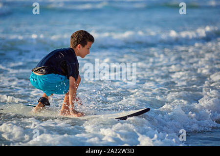 Skilled teenager riding surfboard and balancing a long wavy sea Stock Photo