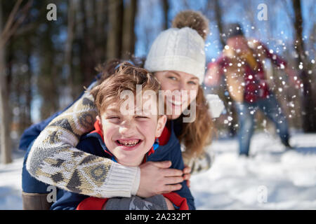 Family of a mother, father and boy child having fun in snow during the winter season and throwing snowballs during a playful fight Stock Photo