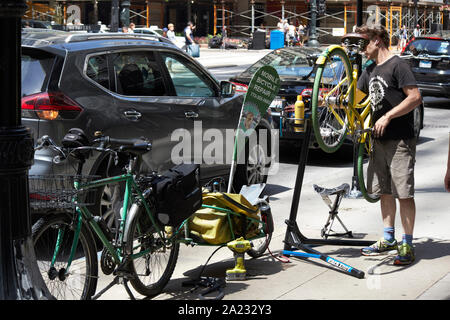 man with mobile bicycle repair business repairing bike on city sidewalk street chicago illinois united states of america Stock Photo