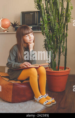 Charming little girl dreaming while reading book Stock Photo