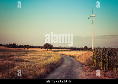 landscape with dirt road through fields in rural area during evening Stock Photo