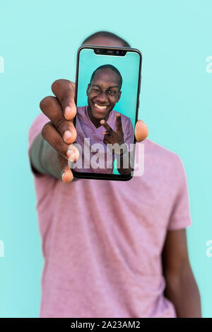Portrait of an african man showing a selfie on his phone Stock Photo