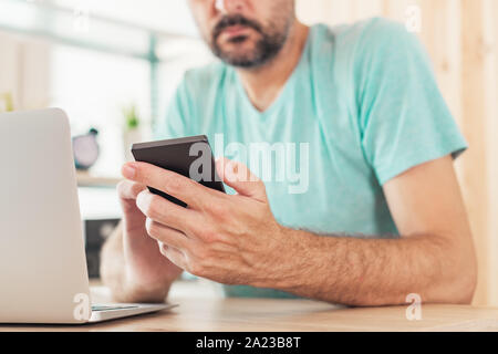 Two-step authentication and verification online internet account login concept. Casual adult caucasian freelancer man is using smartphone and laptop c Stock Photo